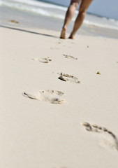 Woman's feet walking on sandy beach
