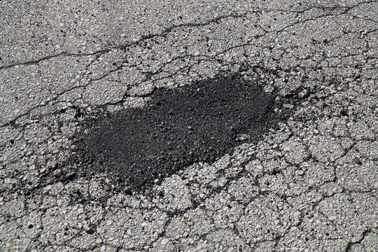 cracked asphalt road surface and repair patch