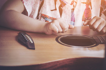 Image processing color tone instagram. Close-up child playing guitar. Concept of liftstyle, learning, hobby, musician, dream and imagination.