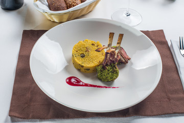 Rack of lamb grilled with porridge of millet on a white plate