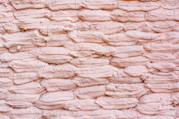 Close up stone wall covered with old pink plaster