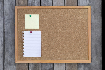 White memo pad and post-it on cork board over wood background
