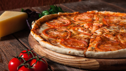 Fresh italian pizza served on rustic wooden table with tomatoes, cheese and parsley. Restaurant menu photo.