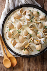 Stewed clam in a creamy sauce with herbs and garlic close-up. Vertical top view