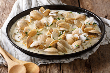 Tasty clams in a creamy sauce with garlic and greens close-up on a table. horizontal