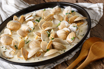 Delicatessen food: clams stewed in cream with garlic and greens close-up. horizontal