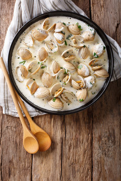 Delicatessen food: clams stewed in cream with garlic and greens close-up. Vertical top view