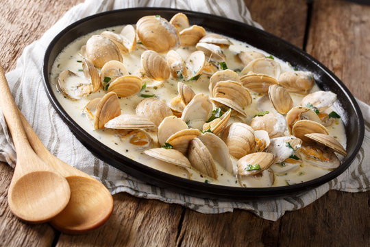 Delicious clams in a creamy sauce with parsley closeup on a plate. horizontal