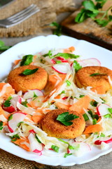 Chickpea cutlets and vegetable salad on a plate. Fried homemade chickpea cutlets. Salad made with cabbage, carrot, radish, green onions and parsley. Vegan lunch or dinner recipe. Rustic style