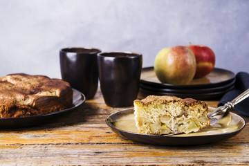 Piece of homemade apple pie, sponge cake "Charlotte" and ripe apples on the vintage wooden table. Selective focus 