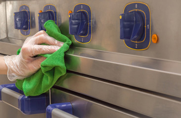 Hand in protective glove with rag cleaning kitchen equipment in the professional kitchen. Stainless...