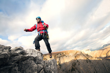 Fototapeta premium Mountaineer jumps over rocks in mountin cloudy weather