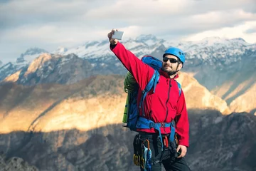 Schilderijen op glas Young mountaineers standing on top of a mountain and make selfie photo © Mediteraneo