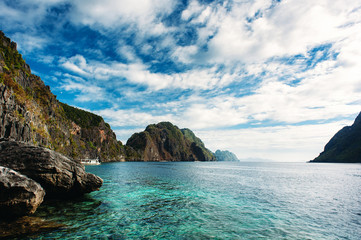 El Nido, Palawan, Philippines. Sharp rocks in lagoon. Blue sky with clouds and clear sea water.