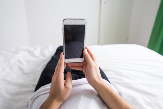 Man In His Bed At Home Looking At Mobile Phone