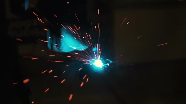 Workers grinding and welding in a factory. Welding on an industrial plant. Slow motion.