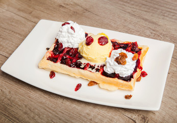 Traditional Belgian waffles with ice cream and berry fruit sauce in the plate,selective focus
