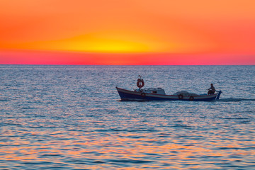 A fisherman departs Alanya Harbor on the Mediterranean sea in Alanya at sunset