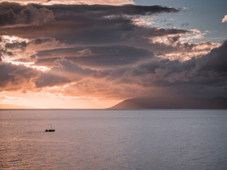 Small boat on sea at sunset
