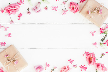 Flowers composition. Gifts and pink flowers on white wooden background. Flat lay, top view
