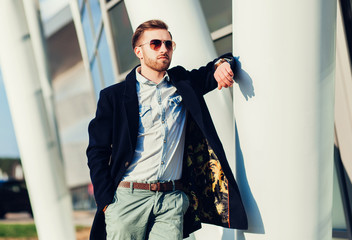 Stylish young handsome man in coat near business centre. People, business, fashion and clothing...