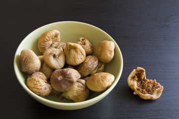 Dried figs in a green plate on a dark background