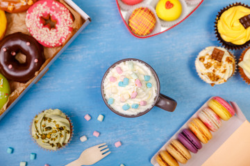 Macaroons, cupcakes and donuts. Mug with whipped cream and marshmallows. Almond macaron cookies. Sweet dessert.