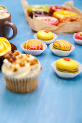 Cupcakes, macaroons and donuts. Mug with whipped cream and marshmallows. Almond macaron cookies. Sweet dessert.