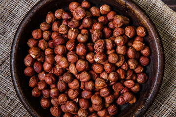 Hazelnut in bowl. Peeled nuts. Organic food on rustic wooden table with sackcloth. Top view.