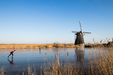 Winter in Kinderdijk in netherlands. A man is sktaing over Ice