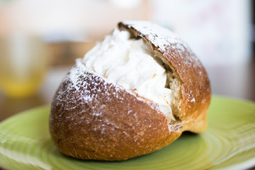 Puffs with cream on a green plate. Italian pastry.Maritozzo con panna