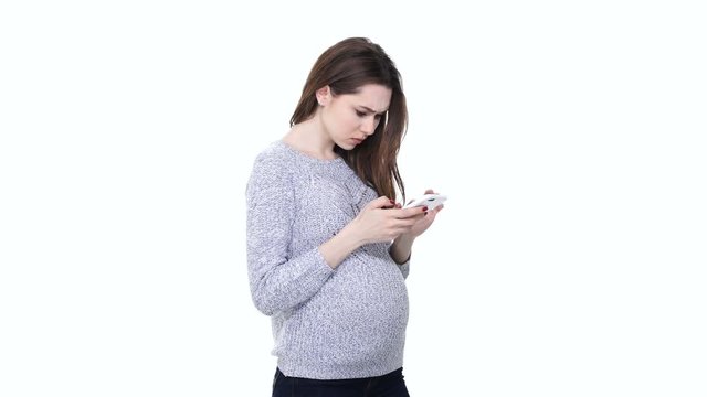 Upset young pregnant woman using mobile phone and receiving bad news isolated over white