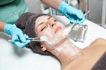beautician applies face mask on beautiful young woman in Spa salon. cosmetic procedure skin care. Microdermabrasion