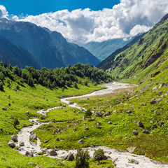 Fototapeta na wymiar Beautiful green mountain valley with a small rough stream illuminated by the sun. Summer russian Caucasus mountains, Elbrus region.