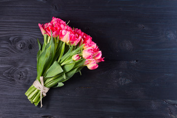 Bouquet of bright pink tulips on black wooden background with copy space