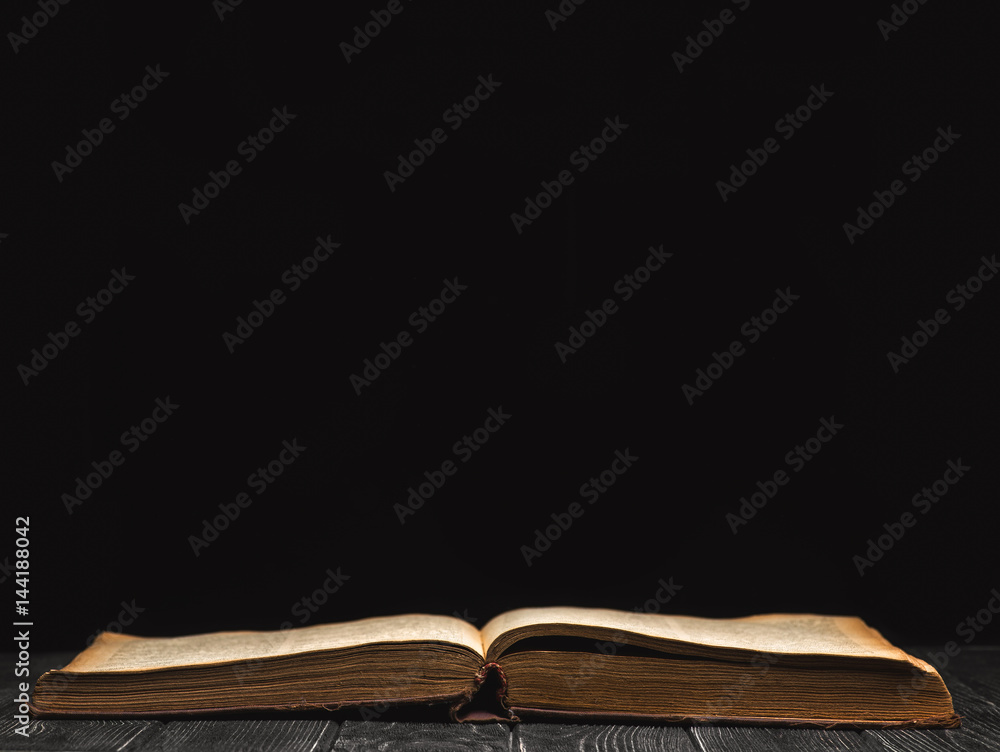 Wall mural Open book on a black background