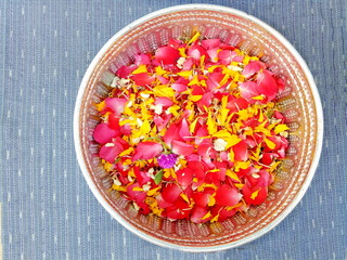 Roses , Marigold and Jasmine petal in silver bowl on blue cotton cloth, Songkran festival in Thailand. Soft focus.