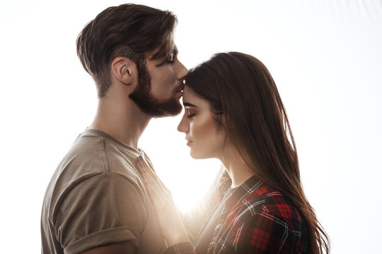 Tender picture of young couple. Man kissing woman to forehead.