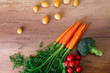 Potatoes with carrot. Red radish, brocoli and raw new potato. Fresh natural vegetables. Organic bio food. On wooden table.