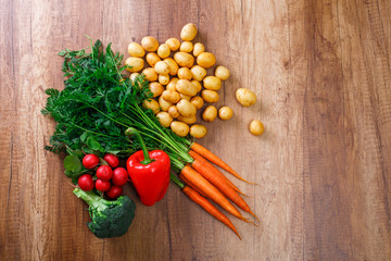 Potatoes with carrot and pepper. Red radish, brocoli and raw new potato. Fresh natural vegetables. Organic bio food. On wooden table.