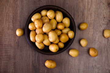 Potatoes in a rustic plate. Raw new potato. Fresh natural vegetables. Organic bio food on wooden table.