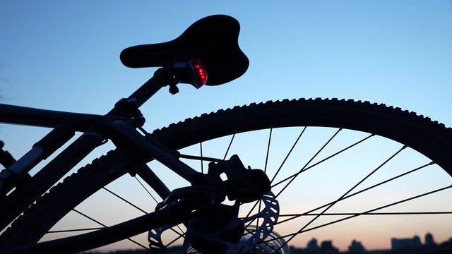Modern Bicycle on the Evening Sunset with Enabled Red Signal Lamp. 4K