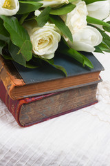 Old books with white flowers close up on romantic lace background