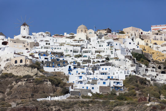 A typical greek village perched on a rock with its white and blue houses and quaint windmills Santorini Cyclades Greece Europe