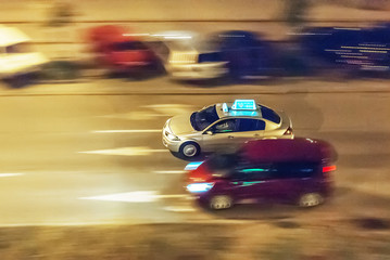 Fototapeta na wymiar Taxi in the nocturnal streets, rushing through the city, panning photo