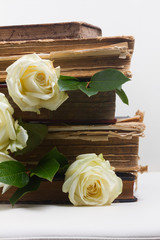 Old books pile with white flowers flowers on white background close up