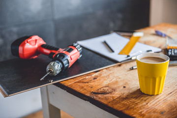 Yellow coffee mug and power drill on the table