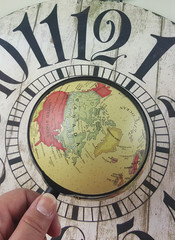 magnifying glass on the world and old wood clock