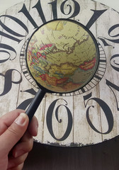 magnifying glass on the world and old wood clock