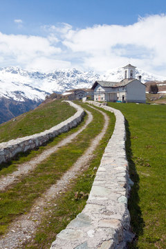 A dirt road between pastures leading to the church of San Rocco in Andossi. Madesimo. Vallespluga. Valchiavenna. Lombardy. Italy. Europe
